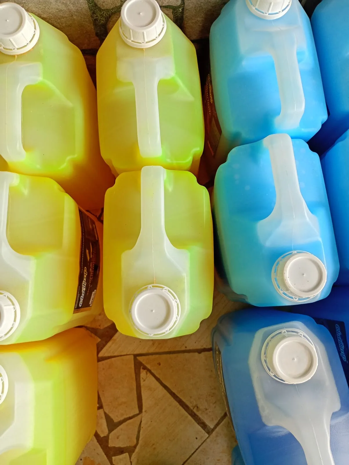 Galões amarelos e azuis de produtos de limpeza, vistos de cima